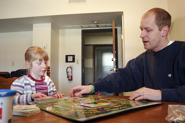 Doug Cutchins '93 and his daughter Bea Geissinger-Cutchins play a board game while staying in the Langan RLC apartment last weekend. As SGA encourages the administration to develop better relations with students, Cutchins is the first administrator to temporarily reside on campus and attend campus events. - Aaron Barker