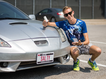 Adam “Salty” Dalton ’16 squats next to his luxury sedan with a fitting vanity plate.   Photo by Matt Kartanata