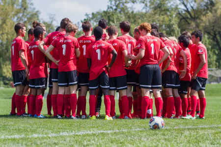 Past and present members of the Grinnell soccer team huddle last Sunday at the alumni match.  Photo by Misha Gelnarova